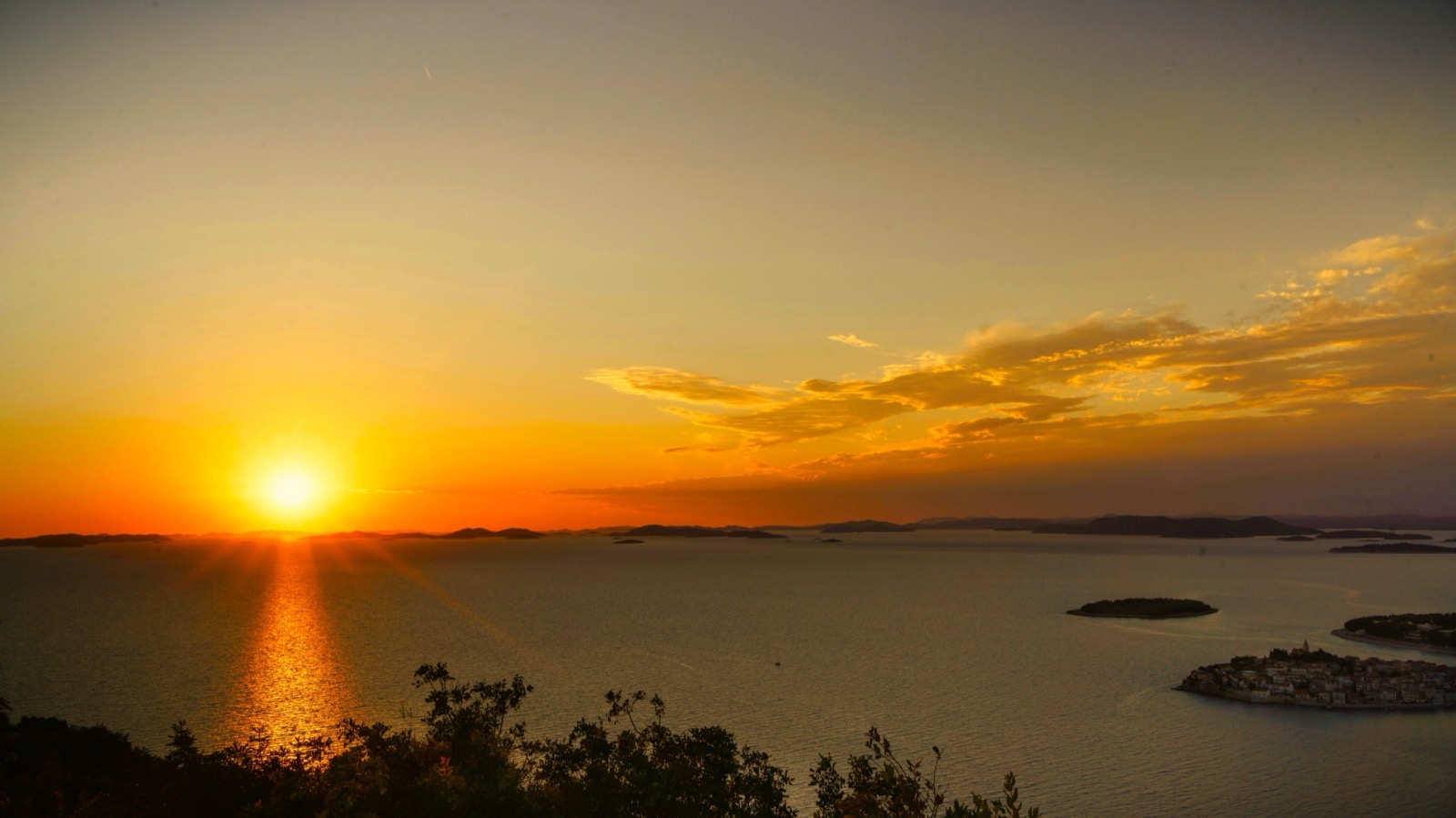 Panoramic view of Primošten peninsula at golden hour with the parish church on top