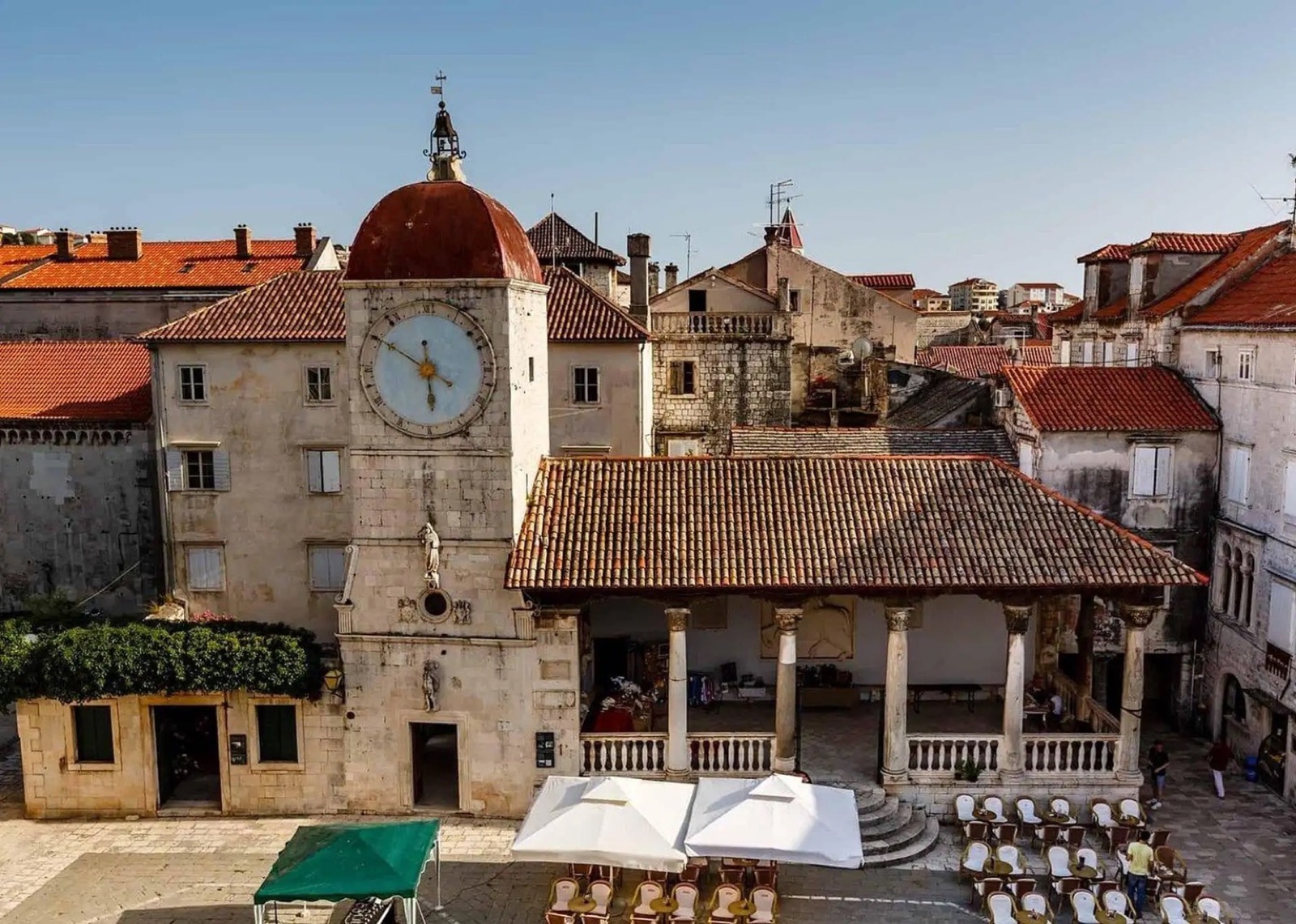 Trogir main square with medieval clock tower and café terraces