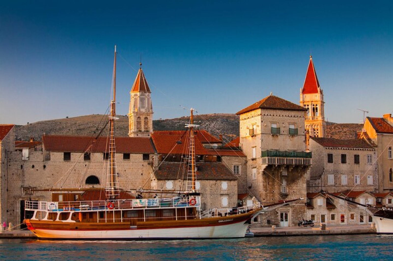 Fishing boats moored along Trogir's waterfront with stone palaces behind